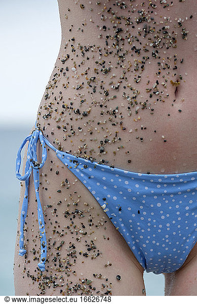 Kleine Strand Steine und Sand auf Frau Körper und Bikini am Strand