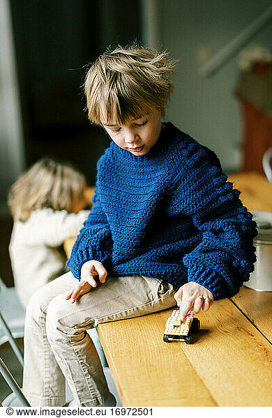 Kleiner Junge in selbstgehäkeltem Pullover spielt mit Bauklötzen