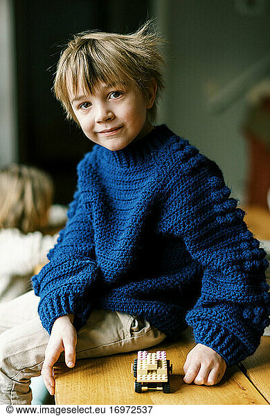 Kleiner Junge in selbstgehäkeltem Pullover spielt mit Bauklötzen