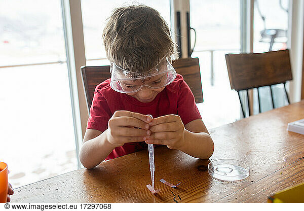 Kleiner Junge macht wissenschaftliche Experimente am Küchentisch