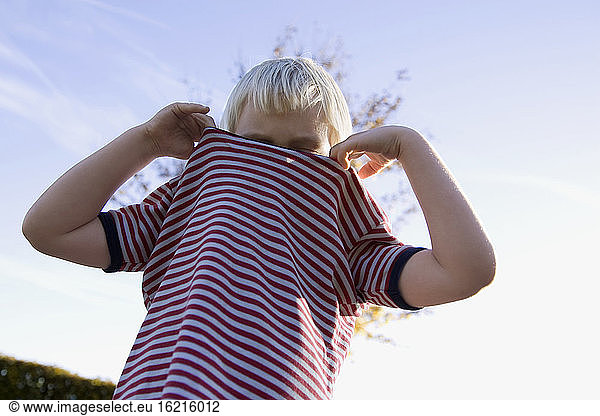 Kleiner Junge (4-5) trägt ein gestreiftes Hemd  flacher Blickwinkel