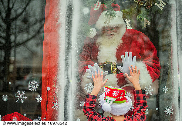 Kleiner Junge trifft den Weihnachtsmann im Fenster