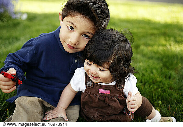 Kleiner Junge und seine kleine Schwester schauen in die Kamera  im Park