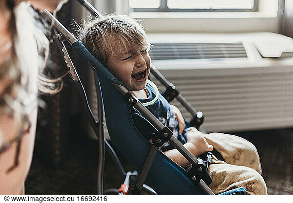 Kleiner weinender Junge in seinem Kinderwagen in einem Hotelzimmer in Palm Springs