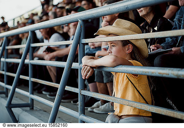 Kleines Mädchen beobachtet das Rodeo mit Cowboyhut