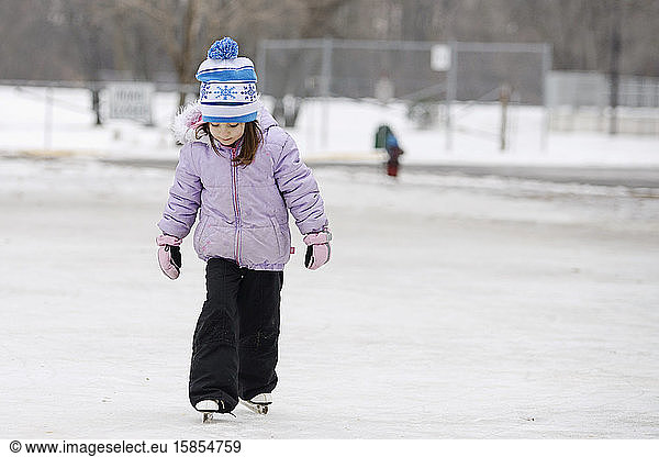 Kleines Mädchen lernt Schlittschuhlaufen im Freien