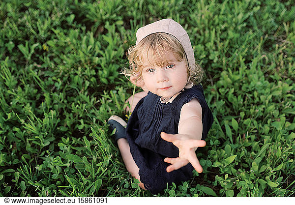 Kleines Mädchen sitzt im Gras.