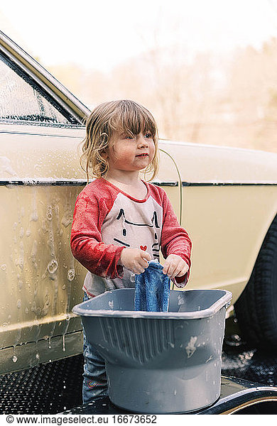 Kleines Mädchen wäscht einen Oldtimer.