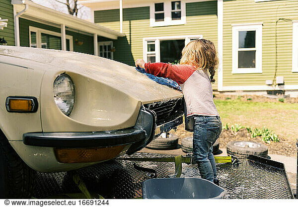 Kleines Mädchen wäscht einen Oldtimer.