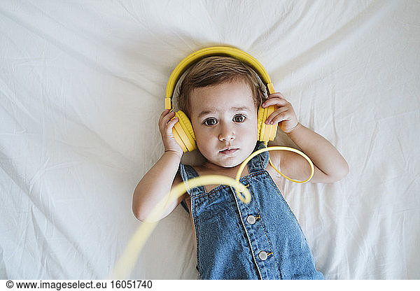 Kleines Mädchen zu Hause beim Musikhören im Bett