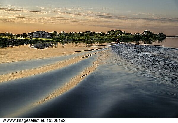 Kleines Motorboot  das bei Sonnenuntergang am Rio Paraguay Wellen schlägt
