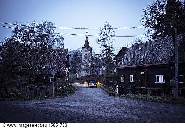 kleines tschechisches Dorf in tiefer Dämmerung Autos Scheinwerfer erhellen die Straße