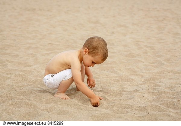 Kleinkind beim Graben im Sand mit der Hand