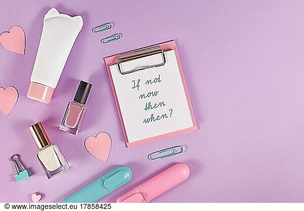 Klemmbrett mit Text Wenn nicht jetzt  wann dann? umgeben von Herzen  Schönheitsprodukten und Schreibwaren auf pastellfarbenem violettem Hintergrund