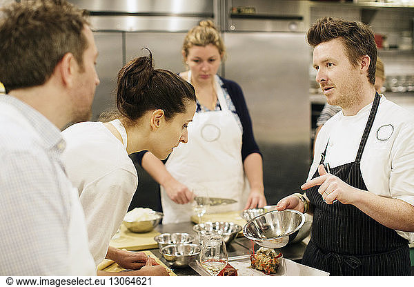 Koch zeigt Studenten in einer Großküche Zutaten