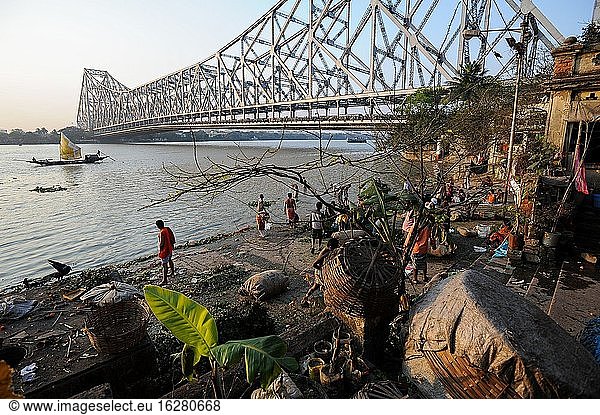 Kolkata (Kalkutta)  Westbengalen  Indien  Asien - Menschen am Mallick Ghat am Ufer des Hooghly-Flusses mit der Howrah-Brücke im Hintergrund  die die beiden Städte Howrah und Kolkata miteinander verbindet.