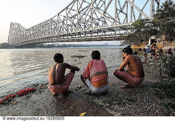 Kolkata (Kalkutta)  Westbengalen  Indien  Asien - Menschen am Mallick Ghat am Ufer des Hooghly-Flusses mit der Howrah-Brücke im Hintergrund  die die beiden Städte Howrah und Kolkata miteinander verbindet.