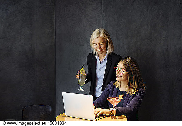 Kollegen diskutieren über die Arbeit  am Laptop  trinken nach der Arbeit Cocktails