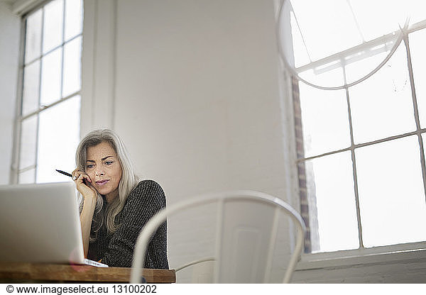 Konzentrierte Frau arbeitet am Laptop am Tisch