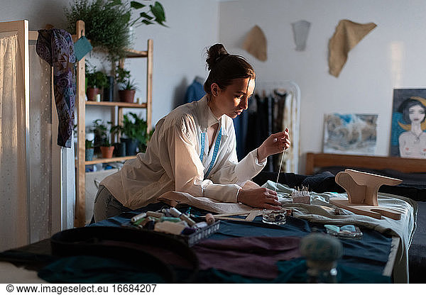 Konzentrierte Frau näht Kleidung im modernen Heimbüro