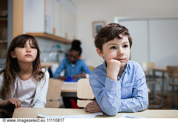 Konzentrierte Kinder sitzen am Schreibtisch im Klassenzimmer
