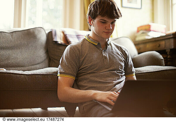 Konzentrierter Jugendlicher mit Laptop auf dem Wohnzimmerboden