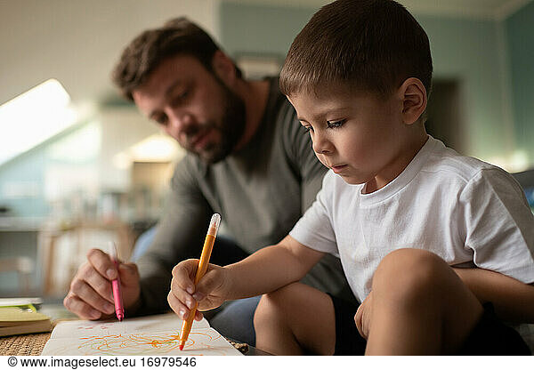 Konzentrierter Junge  der mit seinem Vater zeichnet