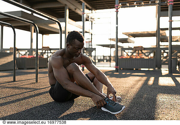 Konzentrierter schwarzer Mann bindet Turnschuh auf Spielplatz