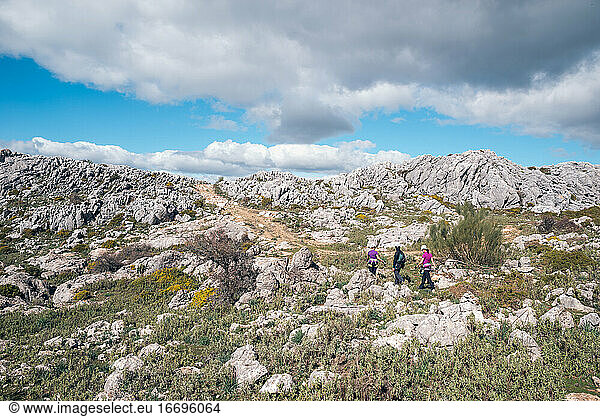 Konzept: Abenteuer. Drei Bergsteiger mit Helm und Klettergurt. Sie wandern in der Ebene auf dem Gipfel des Berges. Kalksteinfelsenlandschaft und niedrige Vegetation. Andalusien  Spanien.