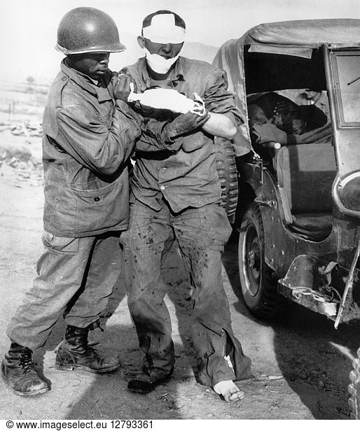KOREA: WOUNDED SOLDIER. An American soldier of the 7th Division is led toward a jeep after being wounded in the fighting on Triangle Hill; the soldier's eyes have been painted out to prevent identification. Photograph  17 October 1952.