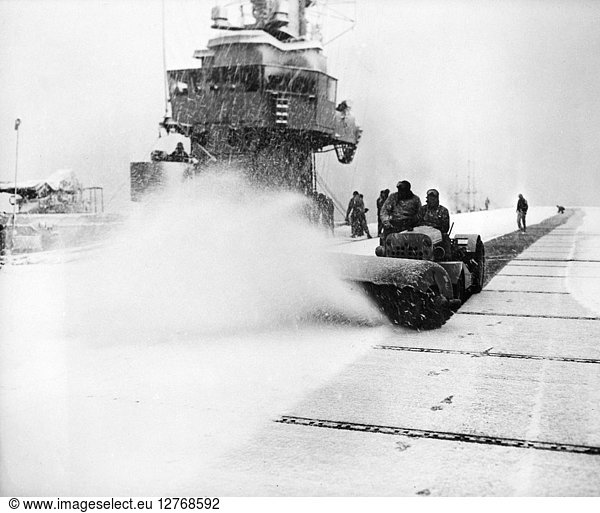 KOREAN WAR: SNOW REMOVAL. Crew members of an unidentified escort carrier off the Korean coast removing snow from the ship's flight deck February 1951.