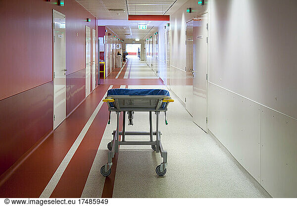 Korridor und Wartebereiche eines modernen Krankenhauses mit Sitzgelegenheiten  einem Rollbett mit blauer Matratze