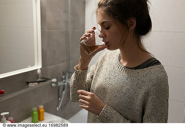 Kranke Frau nimmt im Badezimmer Medikamente ein