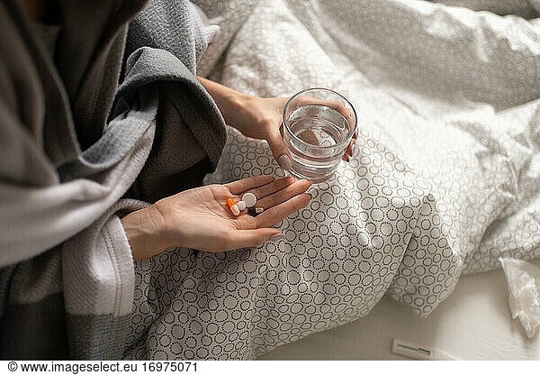 Kranke Frau nimmt Tabletten im Bett