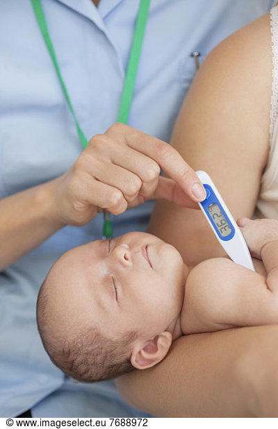 Krankenschwester  die die Temperatur des Babys misst