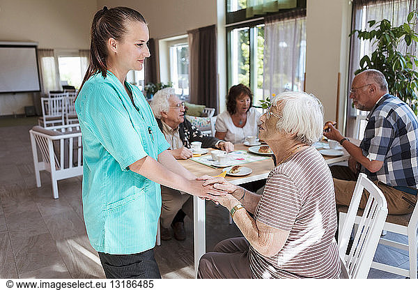 Krankenschwester tröstet ältere Frau beim Frühstück im Pflegeheim