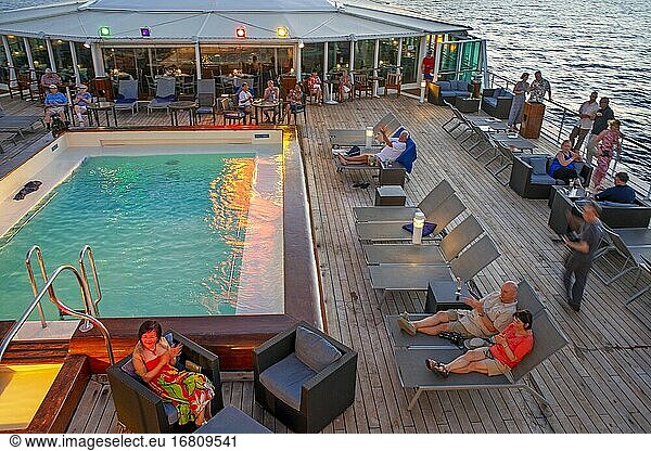 Kreuzfahrtschiff Paul Gauguin  Passagiere entspannen sich auf dem Oberdeck im Schwimmbad. Gesellschaftsinseln  Französisch-Polynesien  Südpazifik.