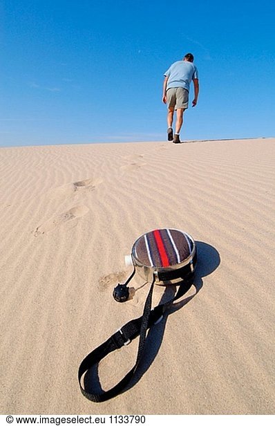 Krumm Mann zu Fuß bis Sanddüne nach Throw away Kantine. Mojave-Wüste. Kalifornien. USA.