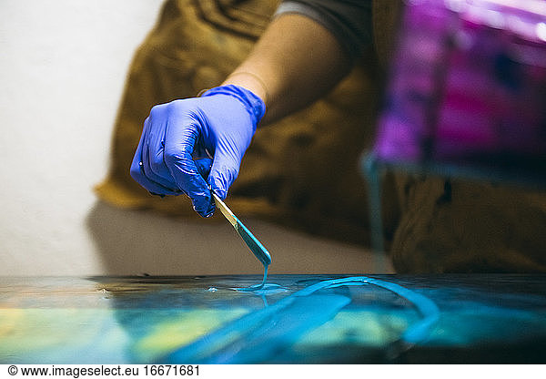 Kunstharzkünstlerin beim Mischen von Kunstharzfarbe mit einfachen Werkzeugen