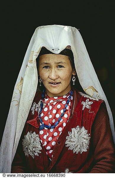 Kyrgyz nomad with traditional traditional traditional traditional traditional traditional traditional traditional traditional traditional costume  white headgear and jewellery at the entrance of a yurt  Bozai Gumbaz  Saradh-e-Broghil  Afghanistan  Asia