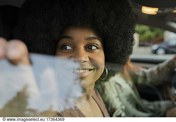Lächelnde Afro-Frau schaut durch ein Autofenster