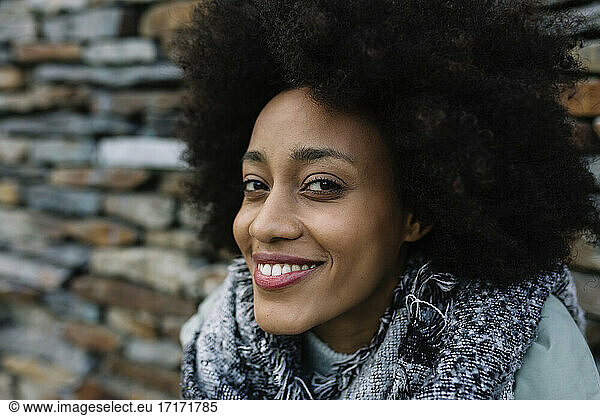 Lächelnde Afro-Frau vor Steinmauer