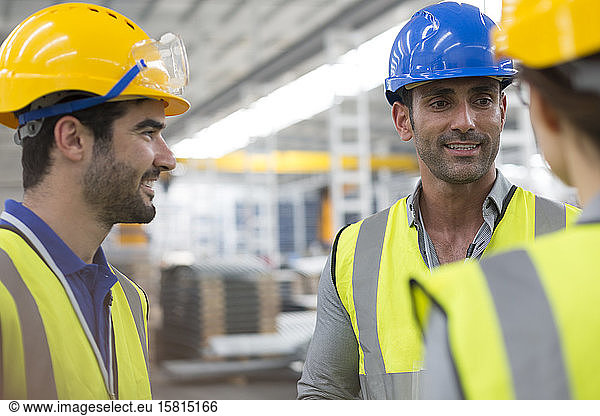 Lächelnde Arbeiter  die sich in einer Fabrik unterhalten