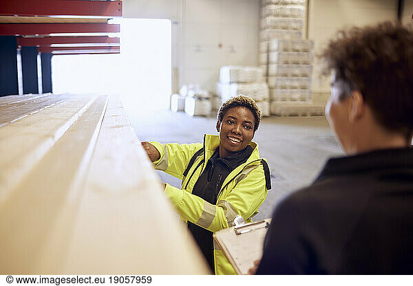 Lächelnde Arbeiterin bei der Arbeit in der Holzindustrie im Gespräch mit einem Kollegen