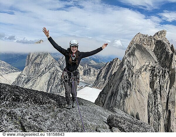 Lächelnde Bergsteigerin auf dem Gipfel einer Felsspitze