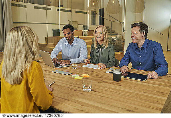 Lächelnde Berufskollegen besprechen die Arbeit im Sitzungssaal