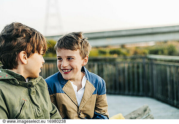 Lächelnde Brüder sitzen bei Sonnenaufgang auf einer Parkbank