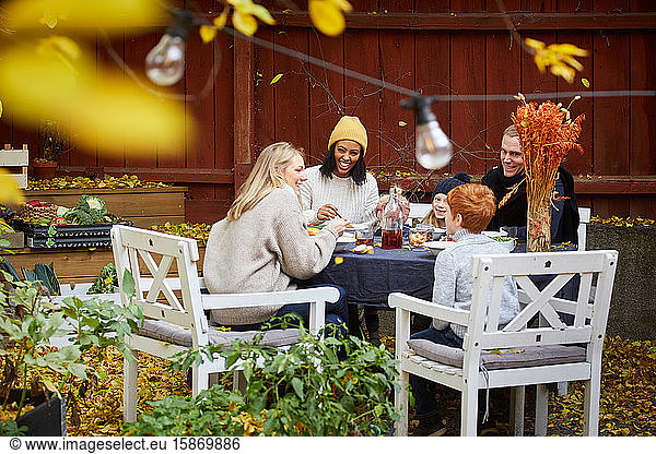 Lächelnde Familie und Freunde sitzen am Tisch für geselliges Beisammensein