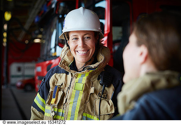 Lächelnde Feuerwehrfrau sieht Mitarbeiterin in Feuerwache an