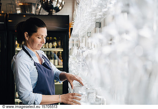 Lächelnde Frau arrangiert Weingläser im Restaurant